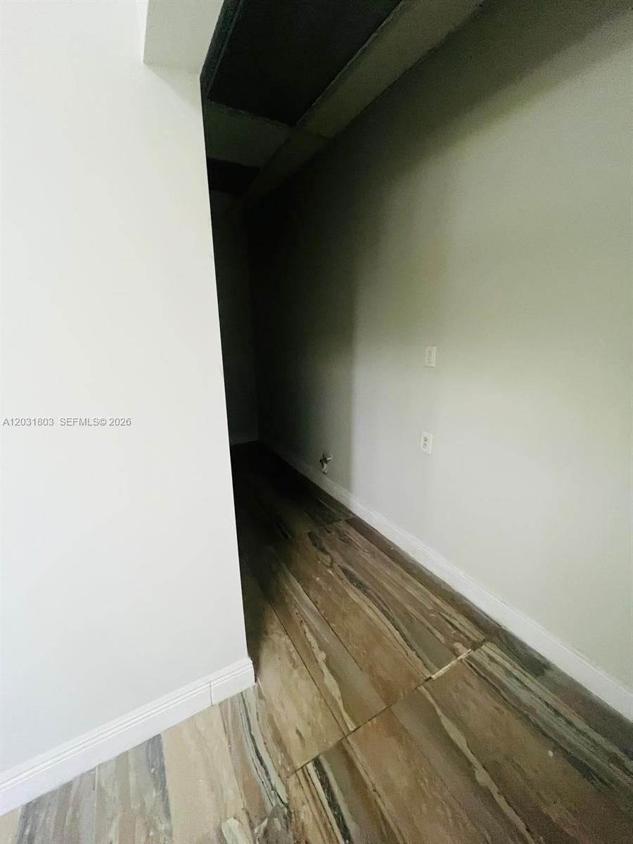 A narrow, dimly lit hallway features light-colored walls and wood-look tile flooring — 6101 W Atlantic Blvd # 205A, Margate FL 33063, MARGATE, FL