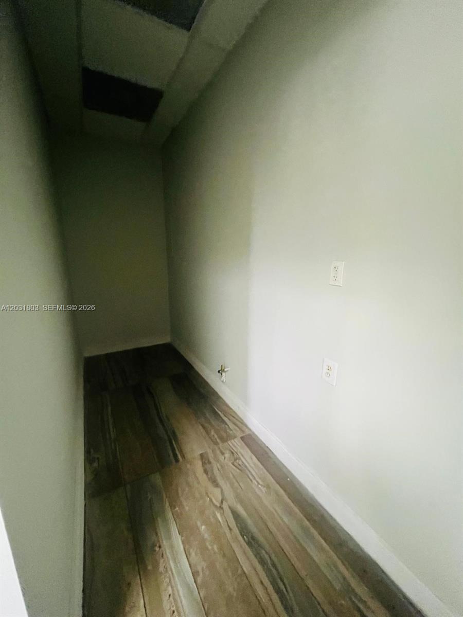 A narrow, empty utility closet features wood-look tile flooring and two electrical outlets on the wall — 6101 W Atlantic Blvd # 205A, Margate FL 33063, MARGATE, FL