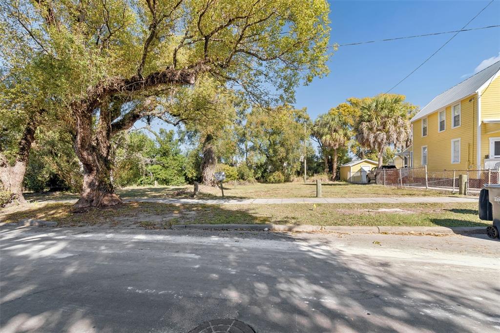 A vacant grassy lot sits between a large tree and a yellow house — 1012 E 12TH AVENUE UNIT 2, TAMPA, FL