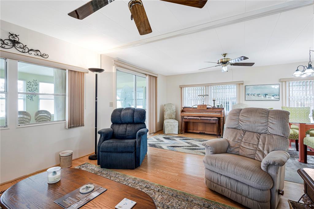 A living room features two recliners, a piano, and hardwood flooring under ceiling fans — 3324 TIKI DRIVE, HOLIDAY, FL
