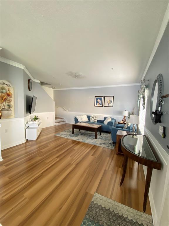 A living room features wood-look flooring, a blue sofa, and a semi-circular console table — 3603 45TH TERRACE W UNIT 101, BRADENTON, FL