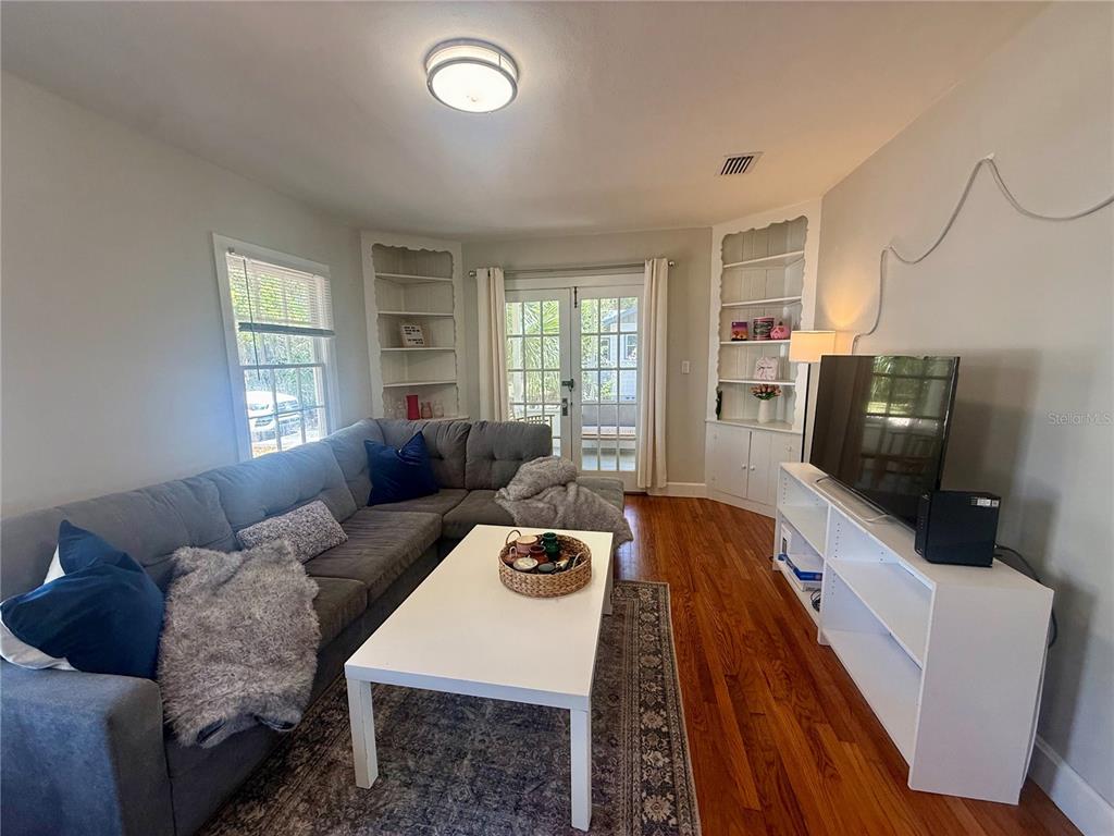 A living room features a gray sectional sofa, white coffee table, and built-in corner shelving — 1741 NW 6TH AVENUE, GAINESVILLE, FL
