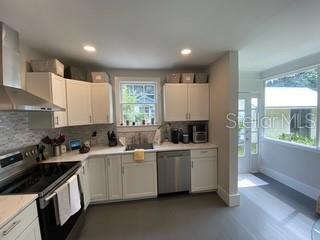 A kitchen with white cabinets, stainless steel appliances, and a window overlooking a sunroom — 1741 NW 6TH AVENUE, GAINESVILLE, FL