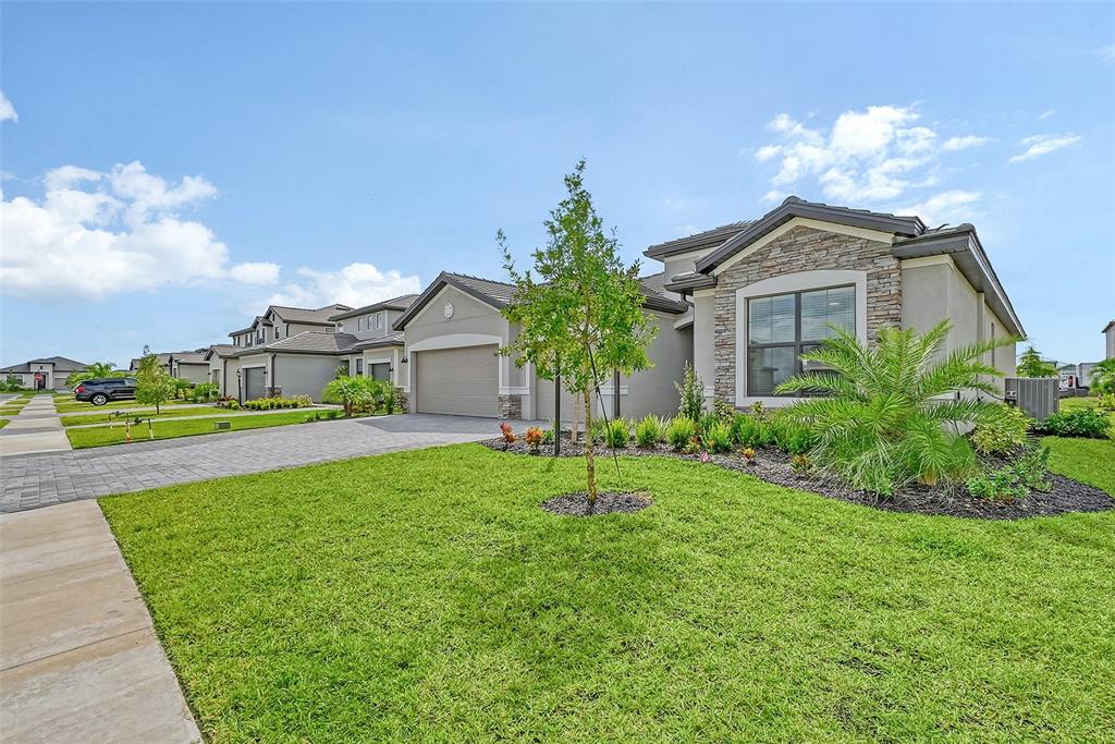 A single-story suburban house with a stone facade, paved driveway, and a manicured front lawn — 15021 SEA SALT WAY, BRADENTON, FL