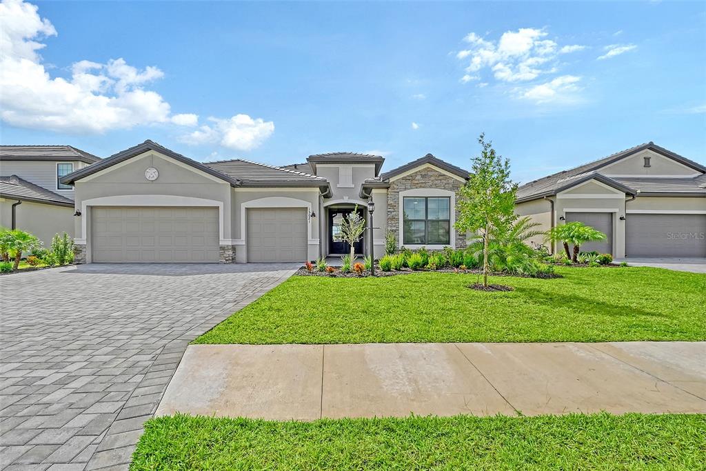 A single-story suburban house with a three-car garage, stone accents, and a paved driveway — 15021 SEA SALT WAY, BRADENTON, FL