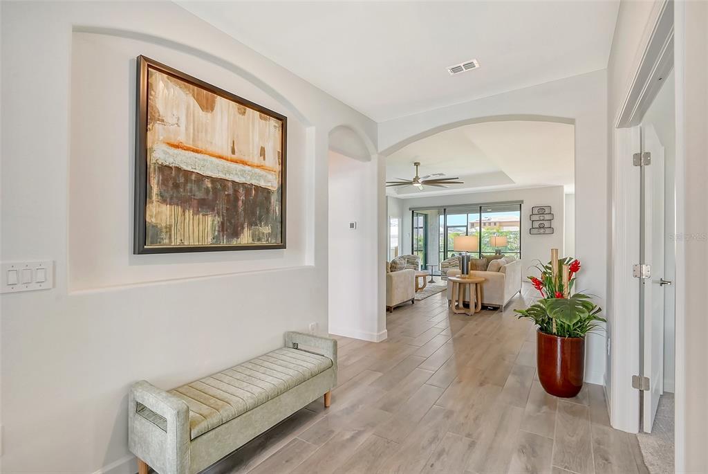 A bright entryway features a light-colored bench, a framed painting, and tile flooring — 15021 SEA SALT WAY, BRADENTON, FL