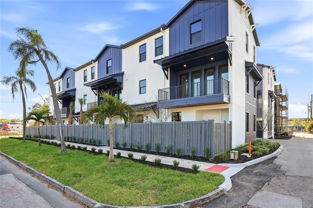 A three-story townhouse with white stucco and blue siding features balconies and a gray fence — 3005 1ST AVENUE N, ST PETERSBURG, FL