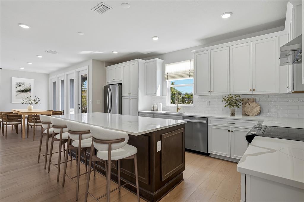 A modern kitchen features white cabinetry, a dark wood island, and light wood flooring — 3005 1ST AVENUE N, ST PETERSBURG, FL
