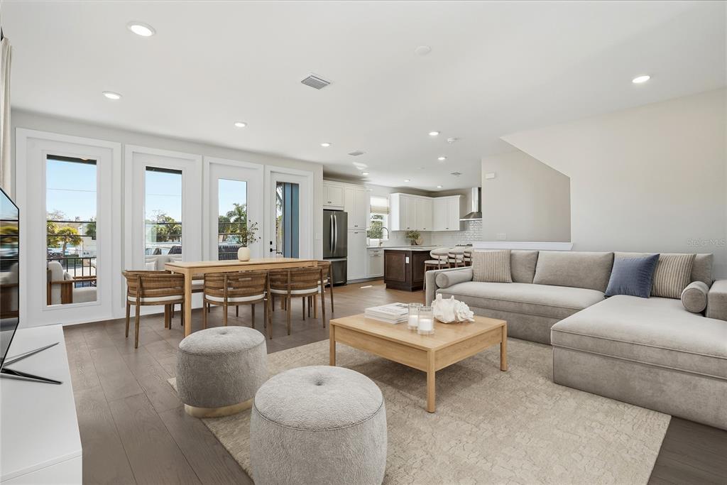 An open-concept living and dining area features wood flooring, a sectional sofa, and kitchen — 3005 1ST AVENUE N, ST PETERSBURG, FL