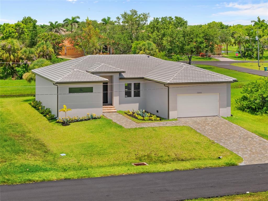 An exterior view of a single-story house with a gray tile roof and paved driveway — 17200 MINT LANE, PUNTA GORDA, FL