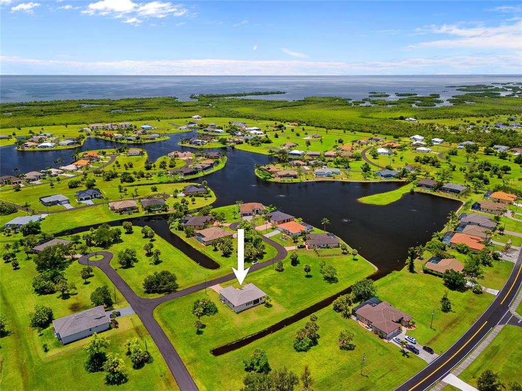 An aerial view shows a single-story house with a gray roof situated on a grassy lot — 17200 MINT LANE, PUNTA GORDA, FL