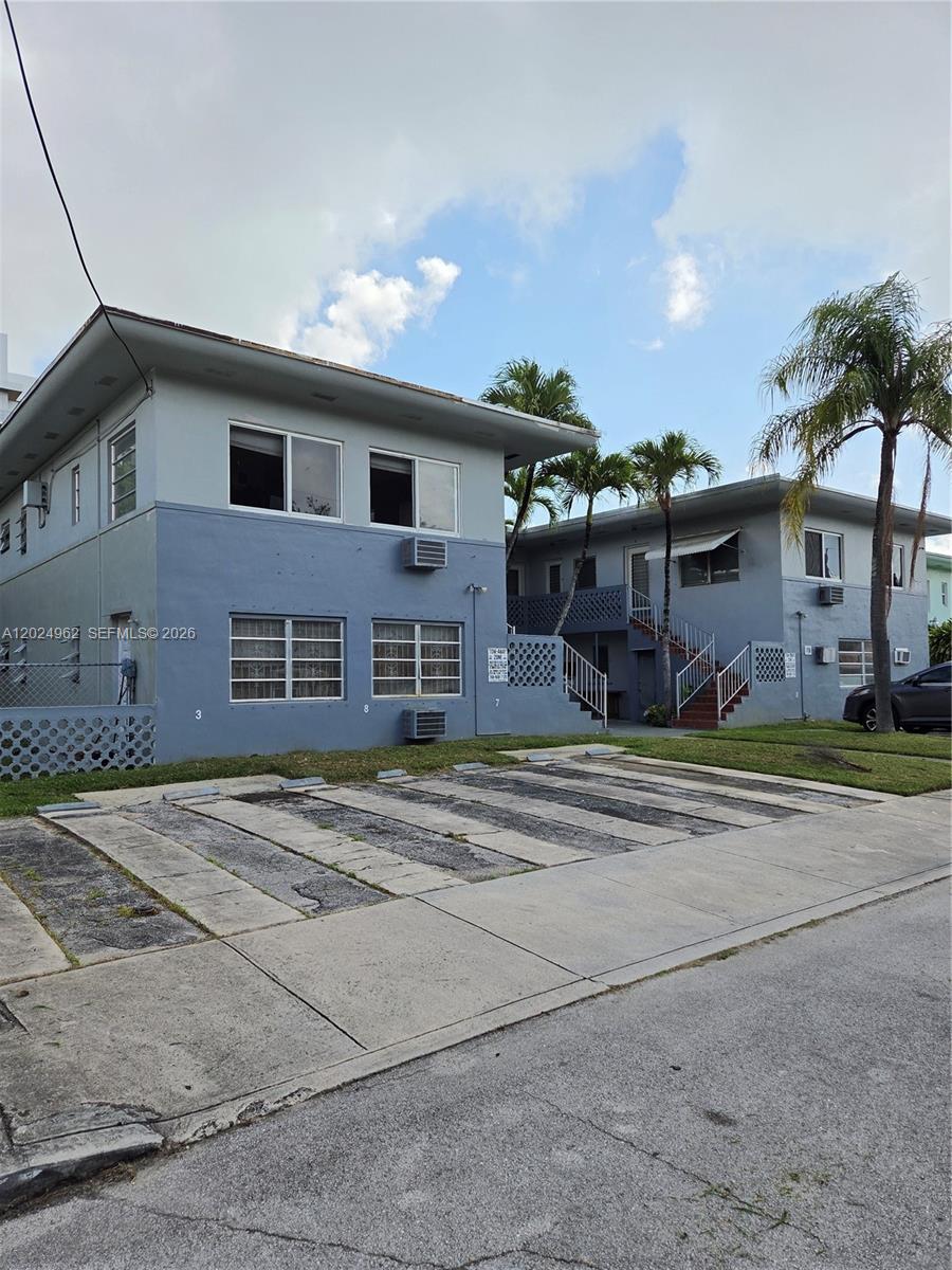 A two-story blue apartment building features exterior staircases and a paved parking area in front — 511 NE 82nd Ter, Miami FL 33138, MIAMI, FL