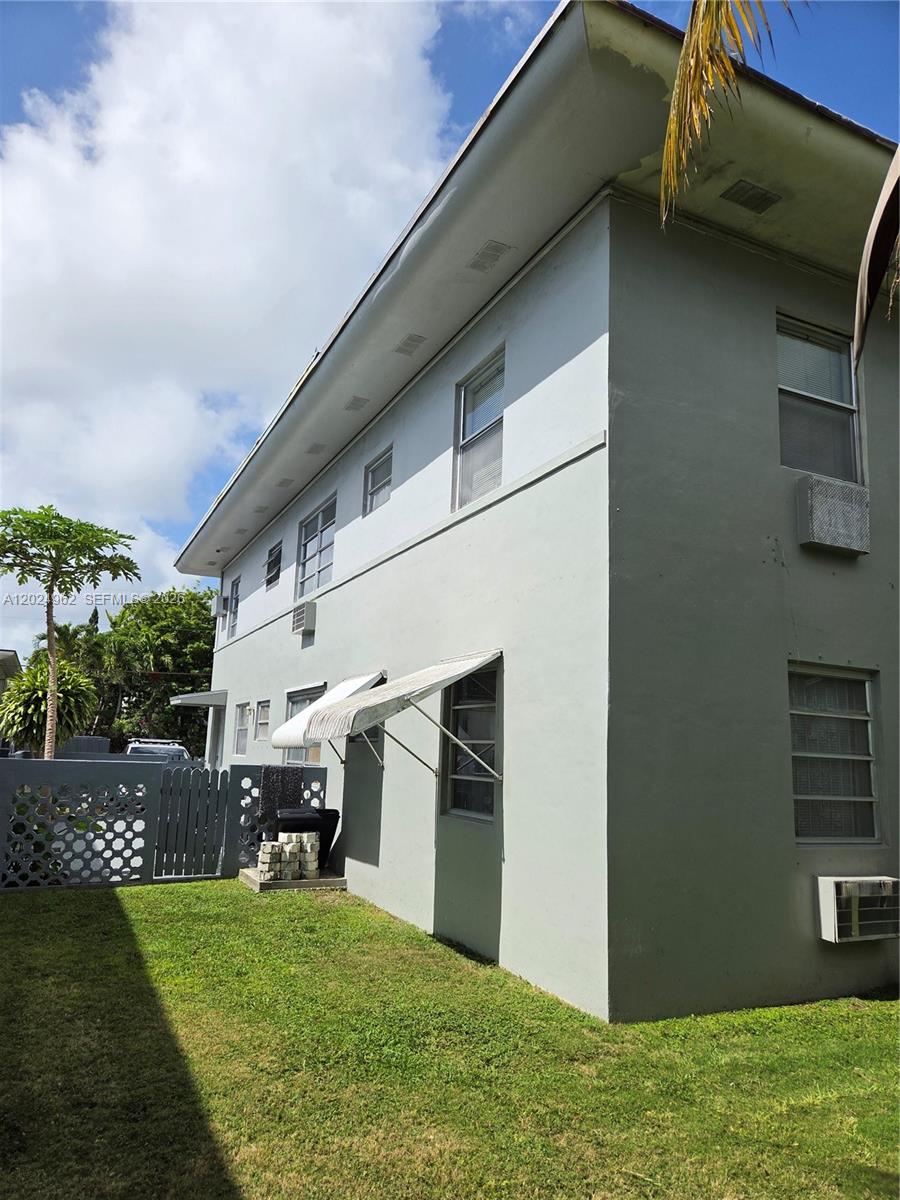 A two-story gray building exterior features a small lawn, a fence, and window awnings — 511 NE 82nd Ter, Miami FL 33138, MIAMI, FL