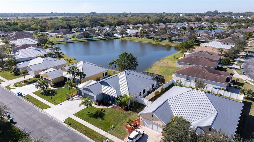 An aerial view of a suburban neighborhood featuring houses with metal roofs surrounding a lake — 102 SALAZAR LANE, SEBASTIAN, FL