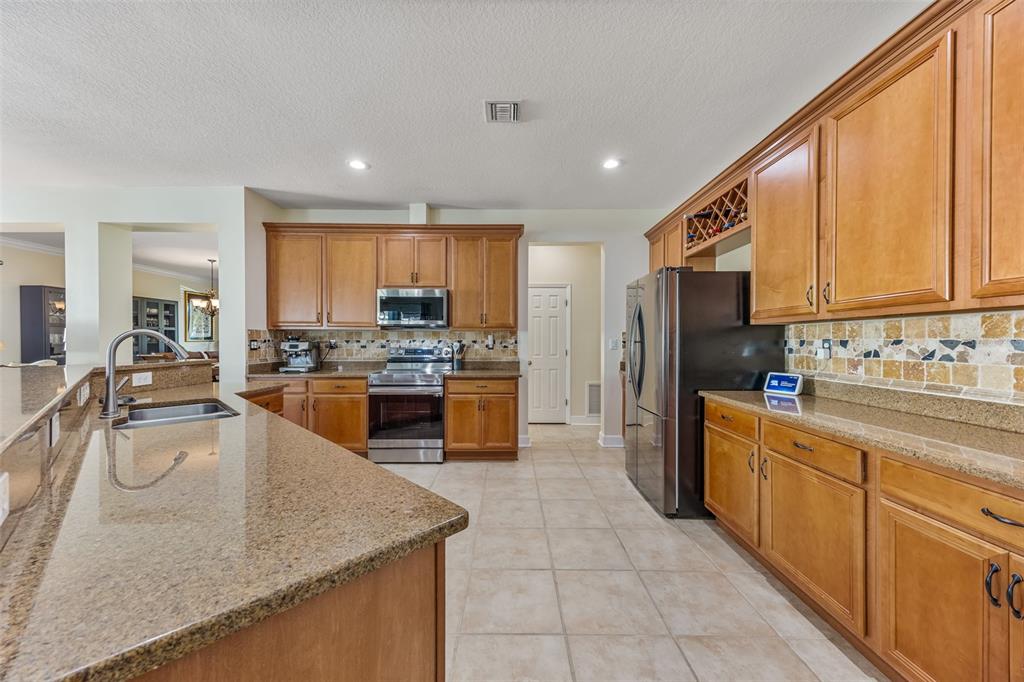 A kitchen with wood cabinets, granite countertops, stainless steel appliances, and tile flooring — 102 SALAZAR LANE, SEBASTIAN, FL