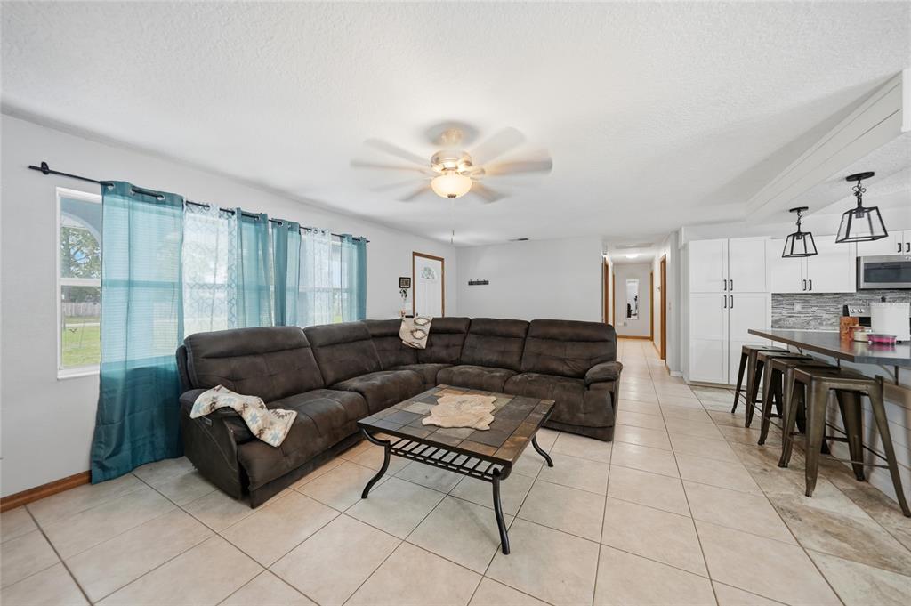 A living room with a large sectional sofa, tile flooring, and an open kitchen area — 2798 SE LOVEJOY STREET, ARCADIA, FL