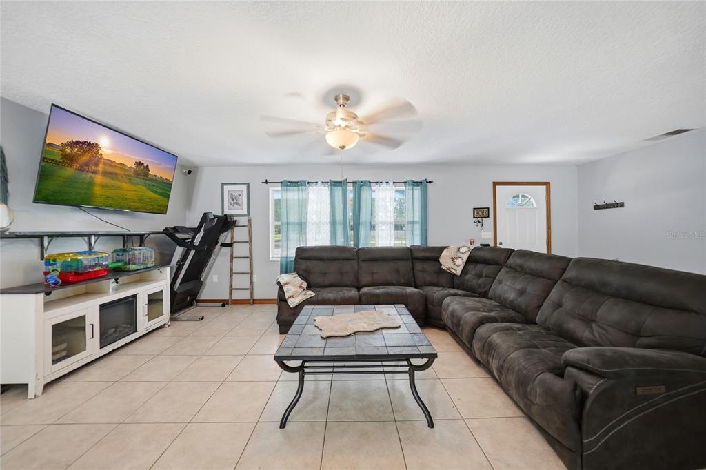 A living room features a large sectional sofa, a coffee table, and a wall-mounted television — 2798 SE LOVEJOY STREET, ARCADIA, FL