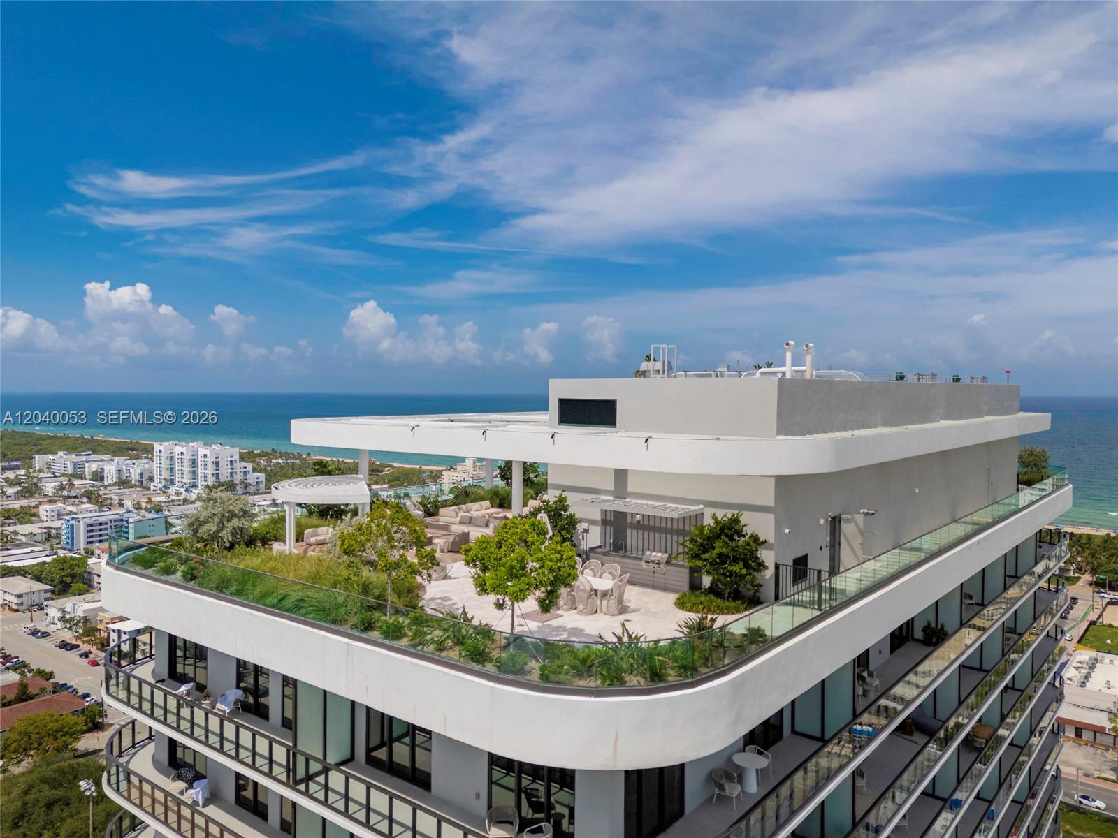 An aerial view of a modern building rooftop terrace featuring landscaping, seating, and ocean views — 580 72nd St # 1008, Miami Beach FL 33141, MIAMI BEACH, FL