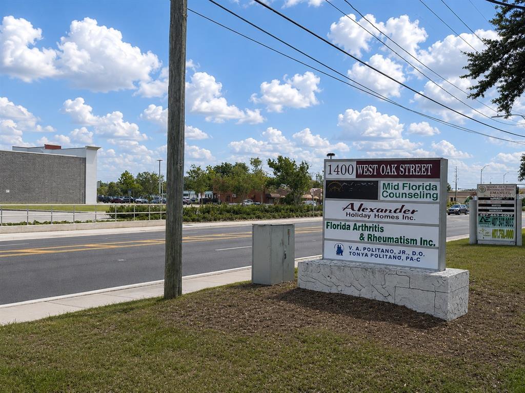 A multi-tenant business sign stands near a road with a building in the background — 1400 W OAK STREET UNIT C1/D2, KISSIMMEE, FL