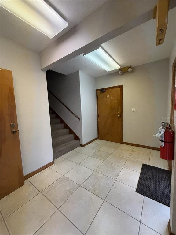 A tiled entryway features a wooden door, a staircase with carpet, and a fire extinguisher — 1400 W OAK STREET UNIT C1/D2, KISSIMMEE, FL