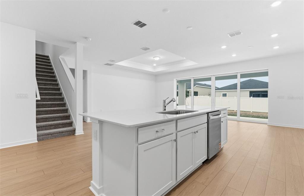 A kitchen island with a sink sits in a bright room with stairs and sliding doors — 6885 SW 90TH PLACE, OCALA, FL