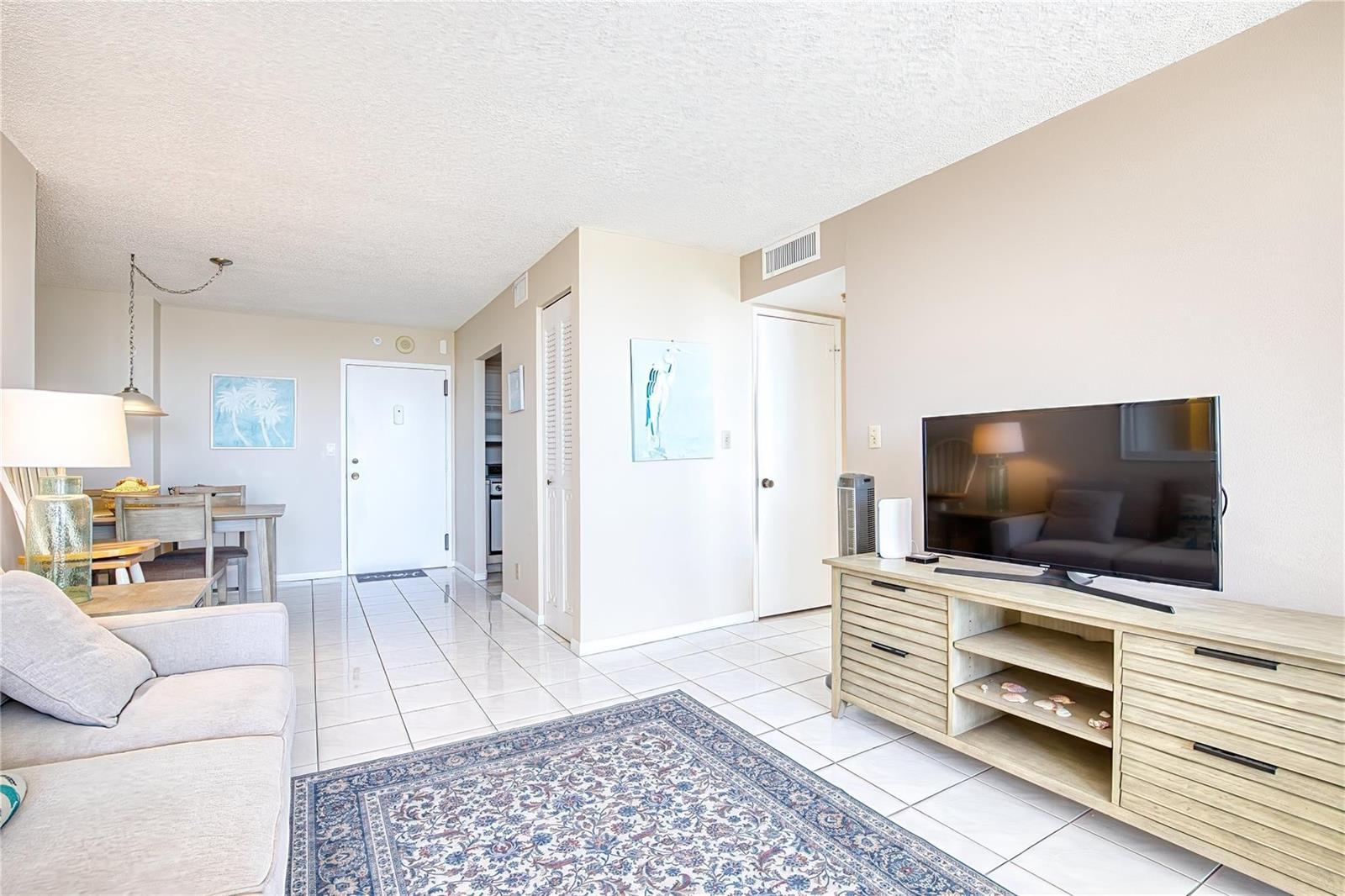 A living room with tile floors, a television console, and a dining area — 111 Briny Avenue # 2312, Pompano Beach FL 33062, POMPANO BEACH, FL