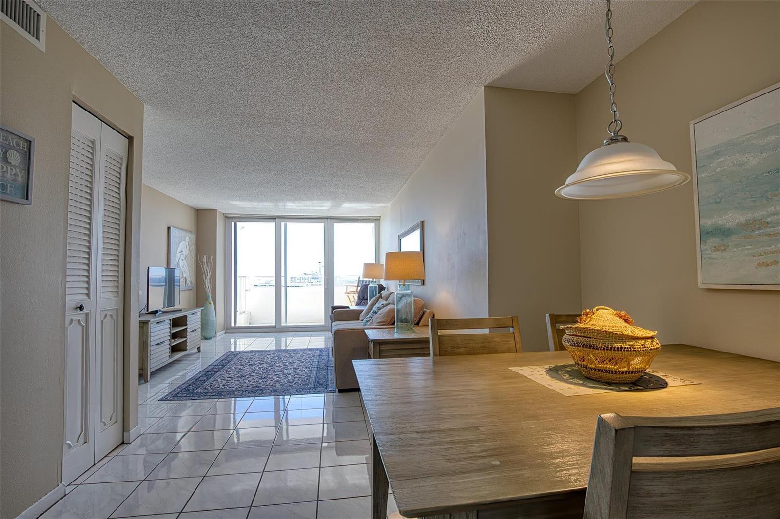 A dining area and living room feature tile floors, a ceiling lamp, and balcony access — 111 Briny Avenue # 2312, Pompano Beach FL 33062, POMPANO BEACH, FL