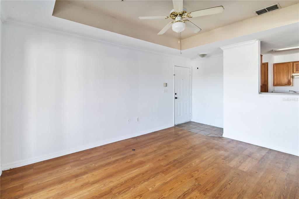 An empty room features wood-look flooring, white walls, a ceiling fan, and an entryway door — 3714 PALM DESERT LANE UNIT 5336, ORLANDO, FL