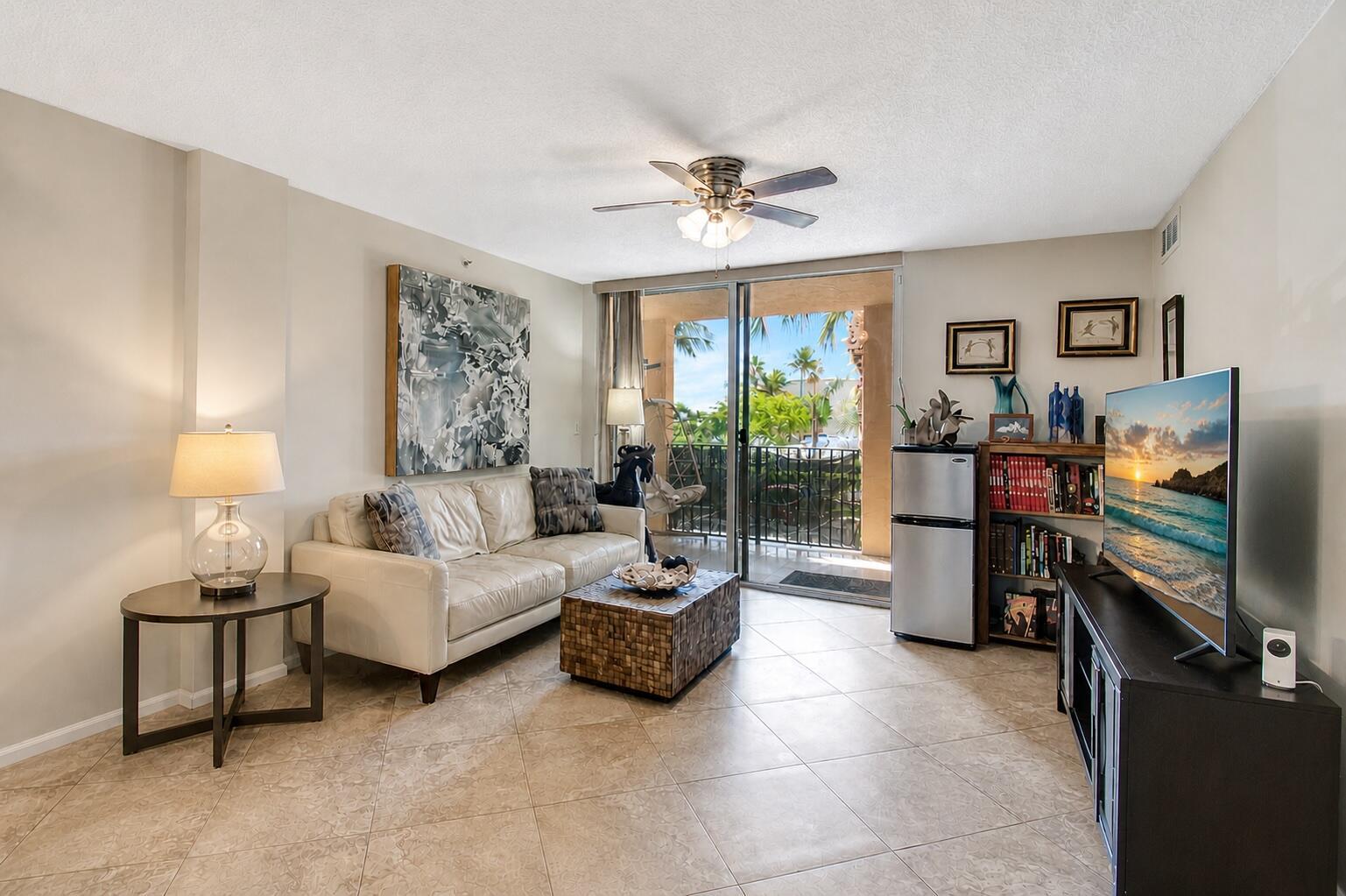 A living room features a white sofa, a coffee table, a television, and a balcony — 1000 Scotia Drive # 204, Hypoluxo FL 33462, HYPOLUXO, FL