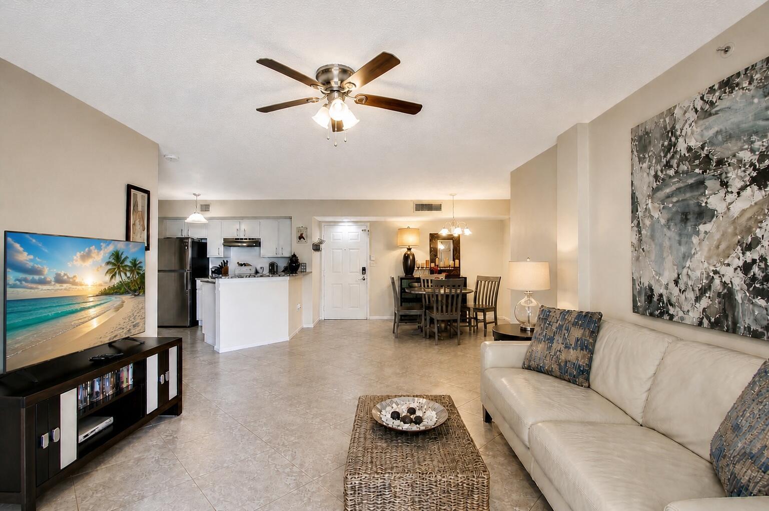 An open-concept living and dining area features tile flooring, a ceiling fan, and white cabinetry — 1000 Scotia Drive # 204, Hypoluxo FL 33462, HYPOLUXO, FL