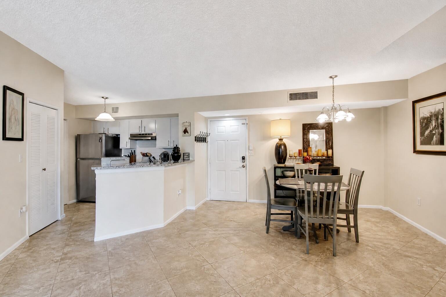 A dining area and kitchen with tile floors, a breakfast bar, and a white door — 1000 Scotia Drive # 204, Hypoluxo FL 33462, HYPOLUXO, FL