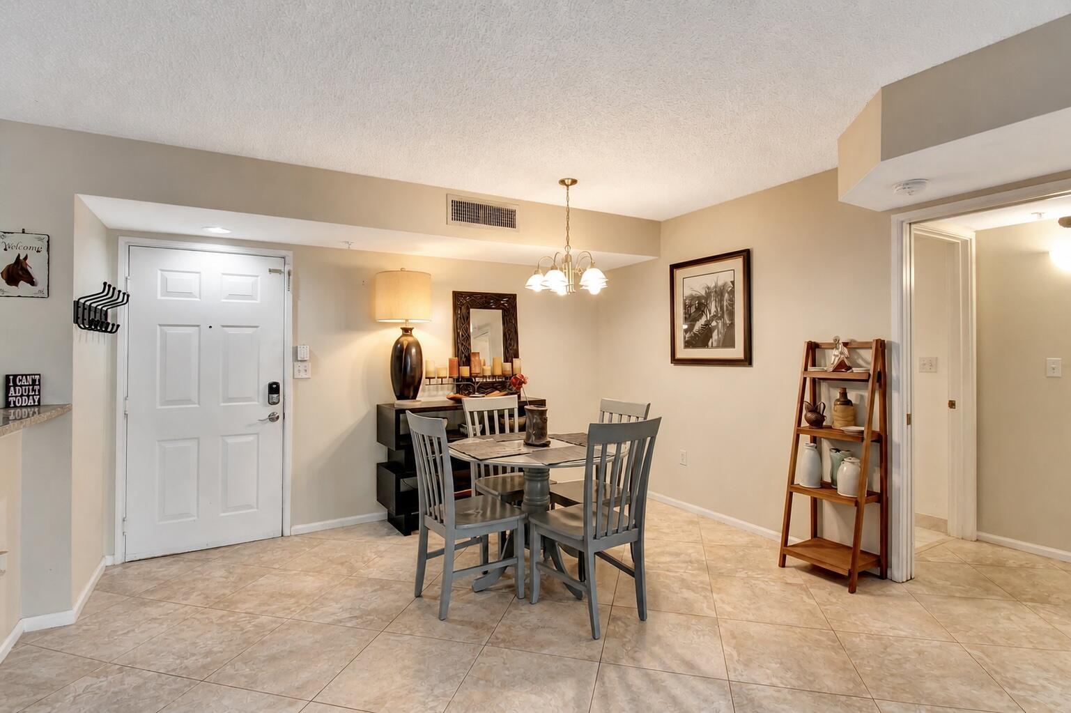 A dining area features a round table with four gray chairs and a wooden shelf — 1000 Scotia Drive # 204, Hypoluxo FL 33462, HYPOLUXO, FL