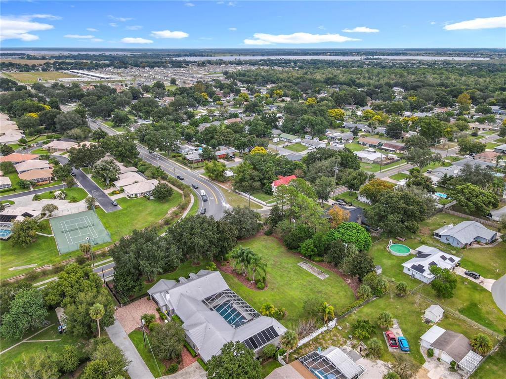 An aerial view shows a residential property with a large yard, pool, and nearby tennis courts — 1414 EDMISTON COURT, AUBURNDALE, FL