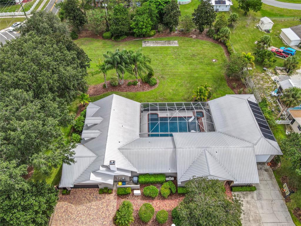 Aerial view of a house with a metal roof, screened pool, and large backyard — 1414 EDMISTON COURT, AUBURNDALE, FL