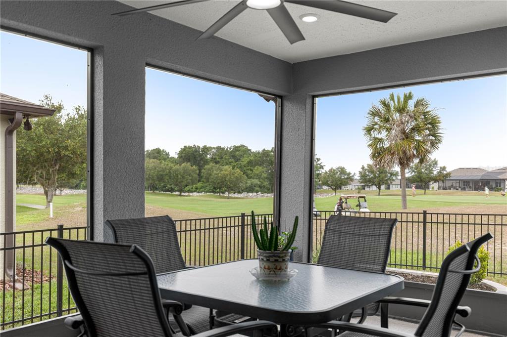 A screened-in patio features a dining set overlooking a golf course and residential neighborhood — 8983 SW 57TH PLACE ROAD, OCALA, FL