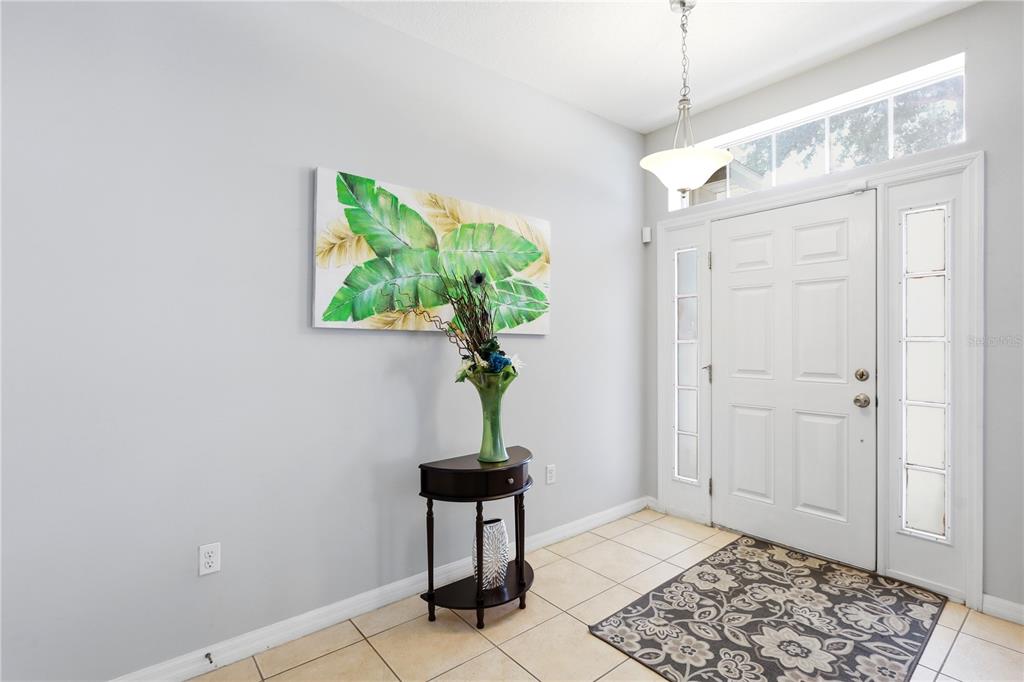 A bright entryway features tile flooring, a half-moon console table, and a white front door — 907 HACIENDA CIRCLE, KISSIMMEE, FL