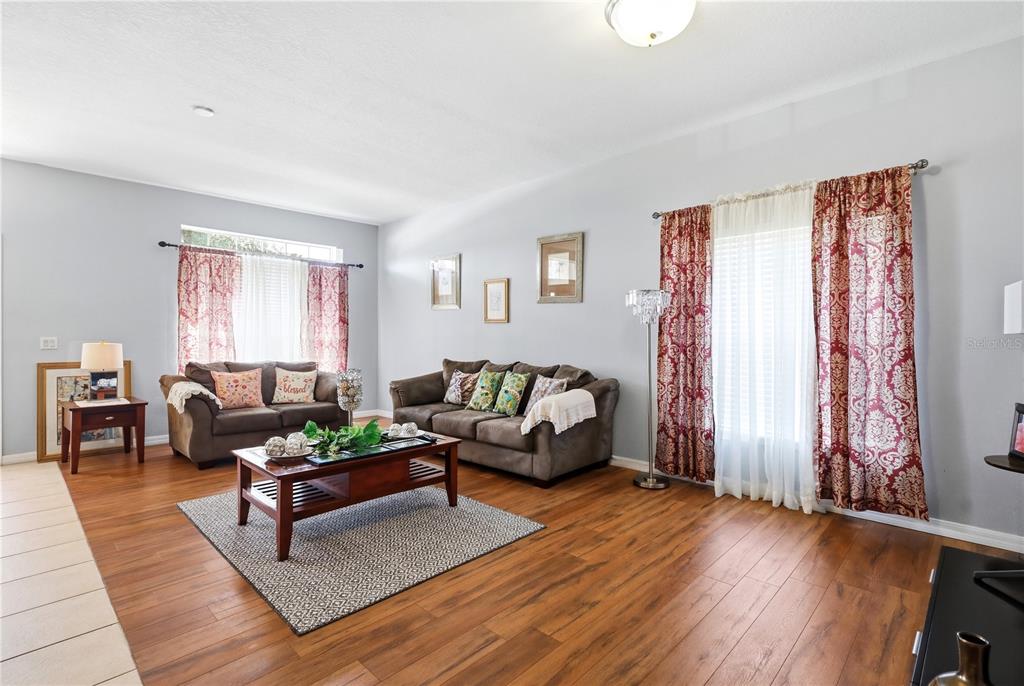 A living room features wood flooring, two brown sofas, a coffee table, and patterned curtains — 907 HACIENDA CIRCLE, KISSIMMEE, FL