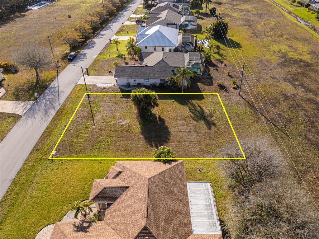 An aerial view shows a vacant rectangular lot outlined in yellow next to a road — 7179 N PLUM TREE, PUNTA GORDA, FL