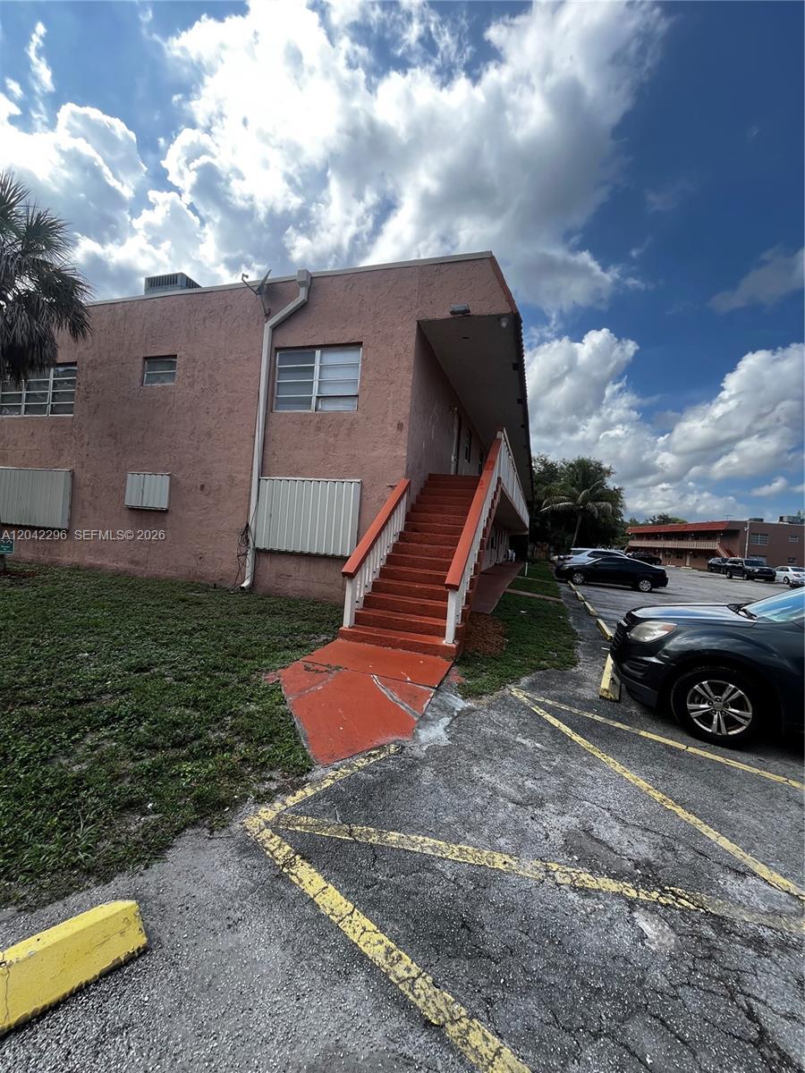 A two-story pink stucco apartment building features an exterior staircase and a parking lot — 7830 NW 33rd St # 206, Davie FL 33024, DAVIE, FL