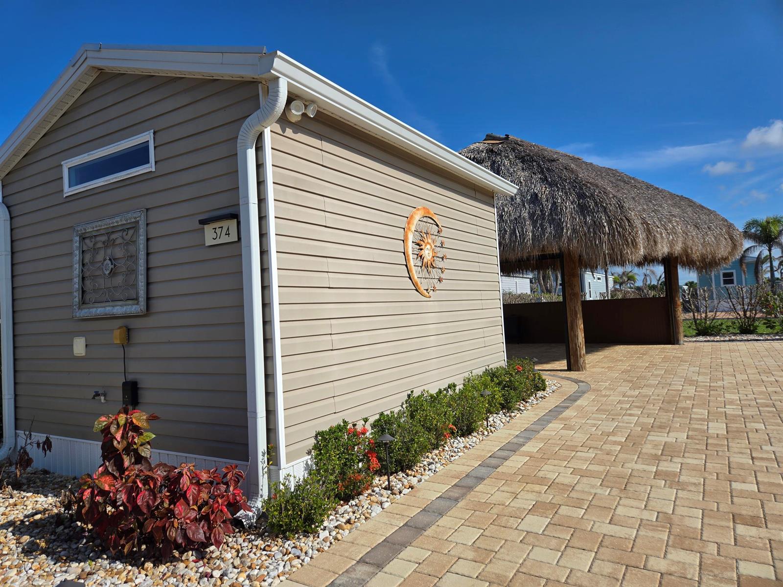 A tan siding house with a sun-and-moon wall decoration and a nearby thatched-roof structure — 639 34th Trace SW, Okeechobee FL 34974, OKEECHOBEE, FL