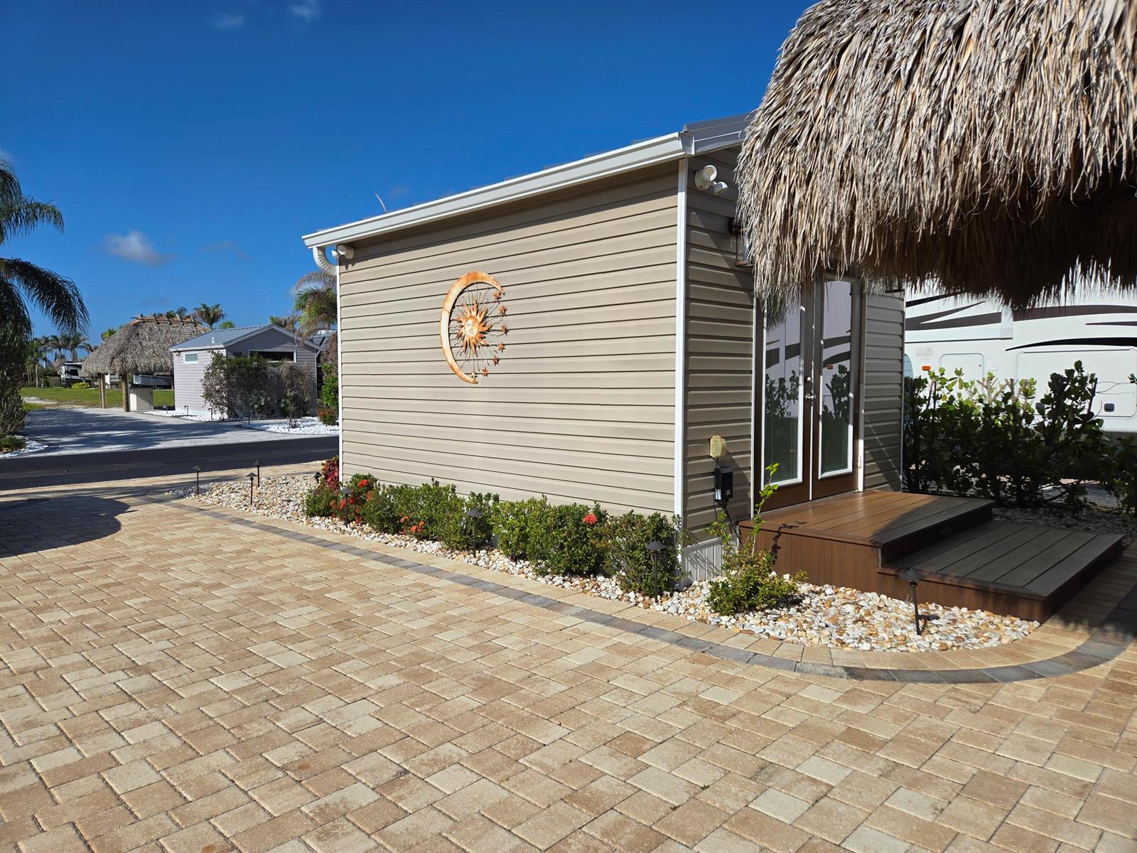 A tan siding structure with a sun and moon wall decoration and a thatched roof — 639 34th Trace SW, Okeechobee FL 34974, OKEECHOBEE, FL