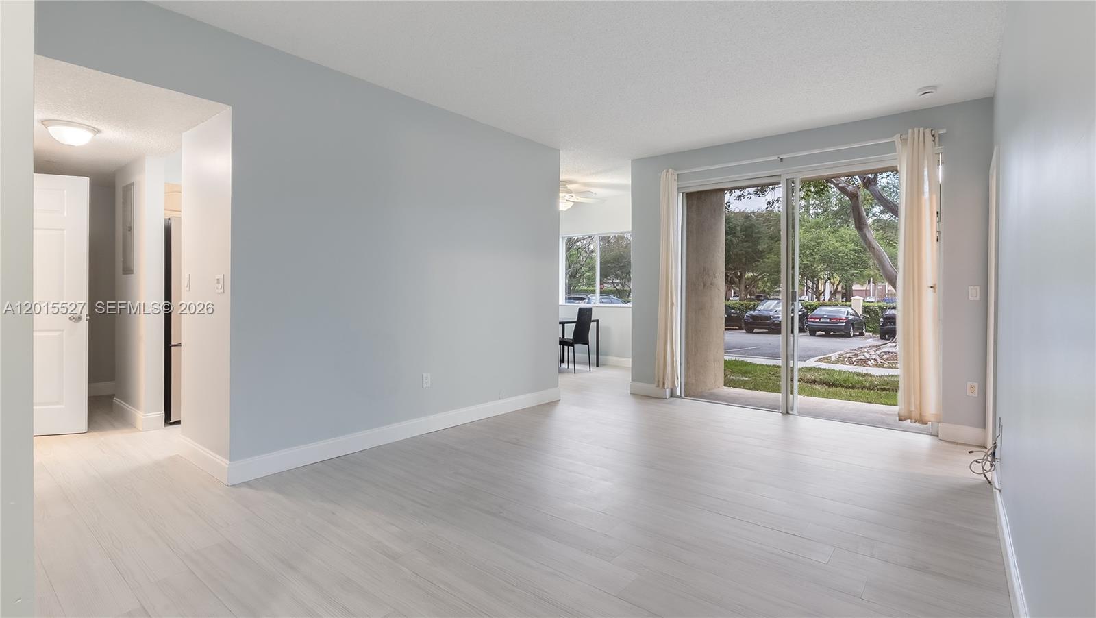 A living room with light-colored flooring, a sliding glass door, and an adjacent dining area — 7085 Nova Dr # 105, Davie FL 33317, DAVIE, FL