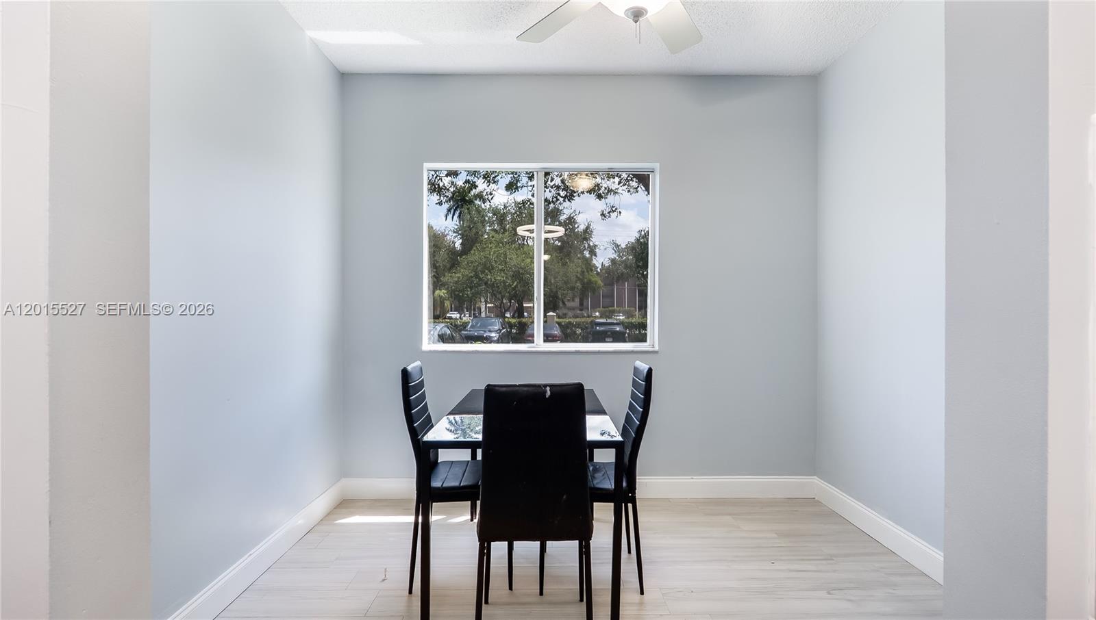 A dining area features light blue walls, wood-look flooring, and a window overlooking a parking lot — 7085 Nova Dr # 105, Davie FL 33317, DAVIE, FL