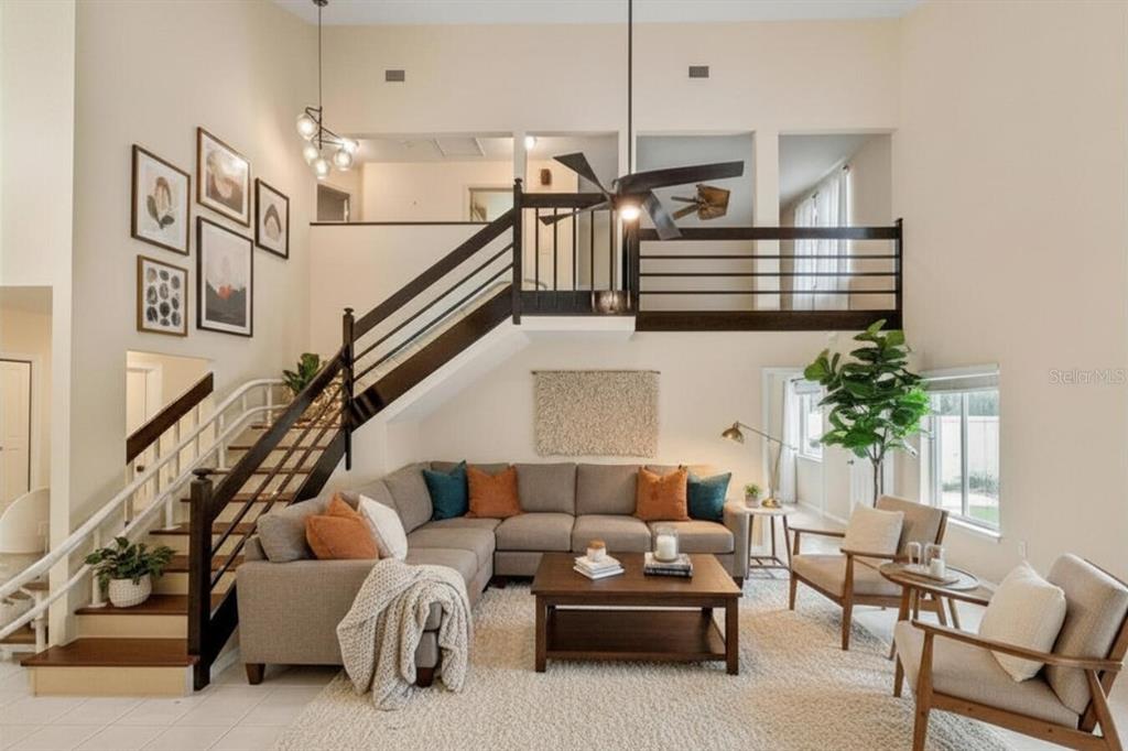 A living room features a sectional sofa, a staircase with dark railings, and a loft area — 4842 WELLBROOK DRIVE, NEW PORT RICHEY, FL