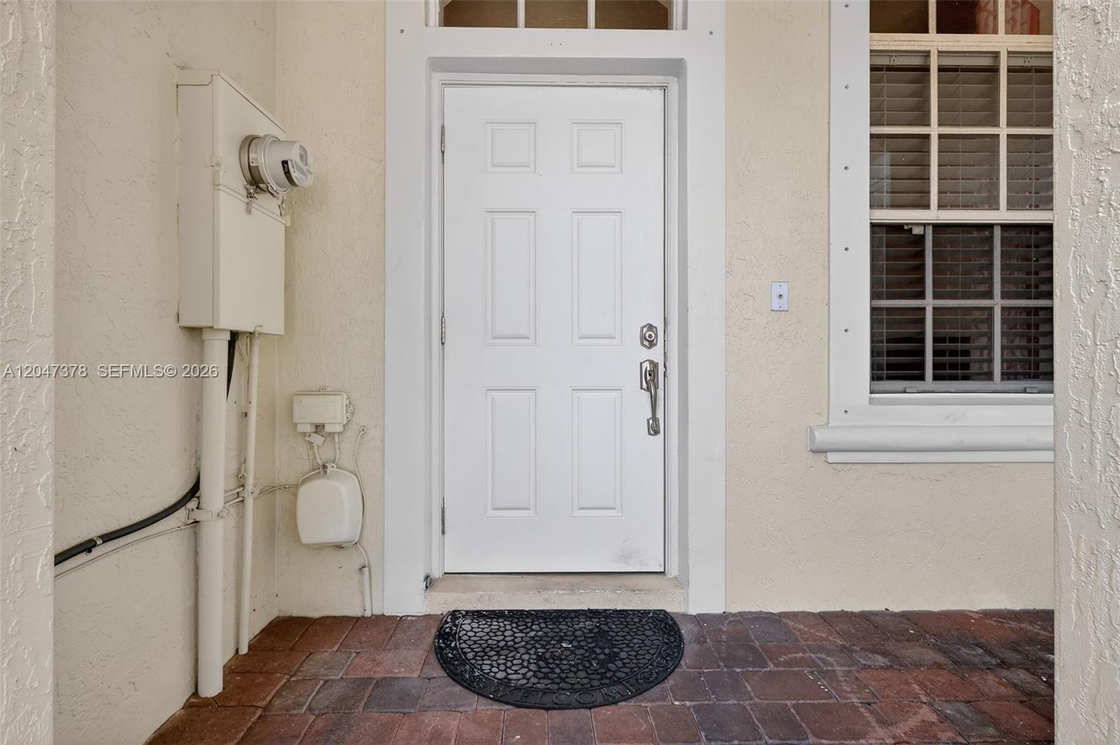 A white front door with a brick porch and an exterior utility meter — 2671 SW 85th Ter # 103, Miramar FL 33025, MIRAMAR, FL
