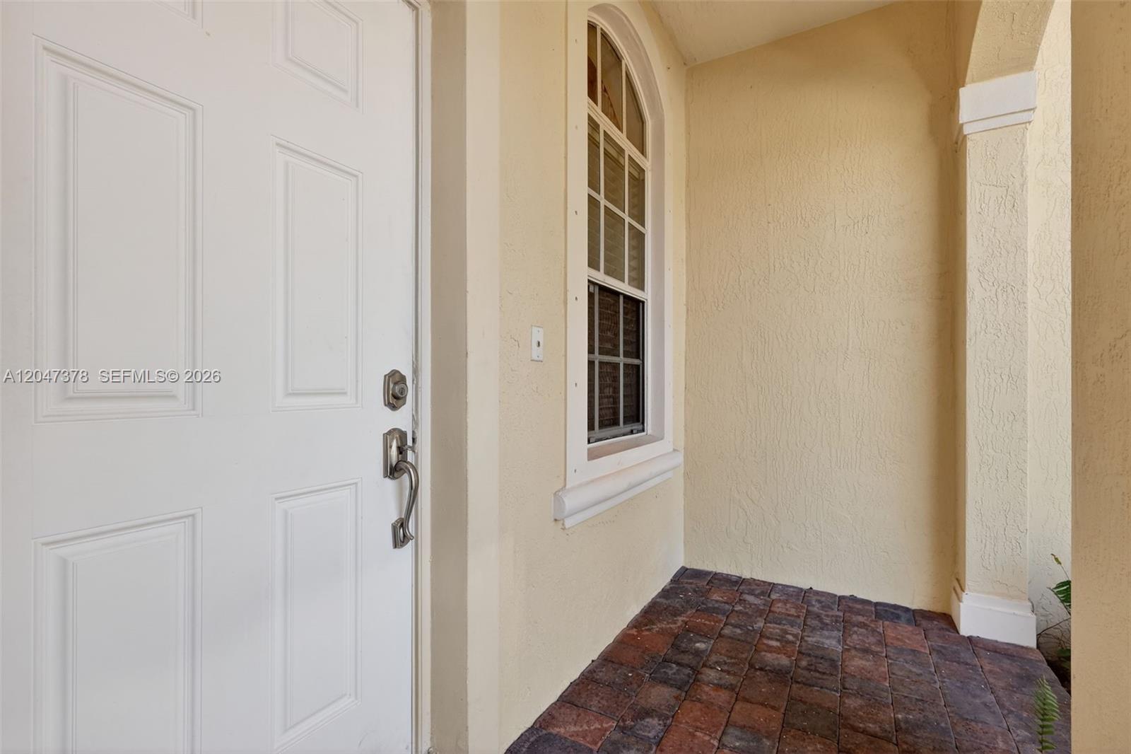 A white front door sits beside an arched window on a paved entryway porch — 2671 SW 85th Ter # 103, Miramar FL 33025, MIRAMAR, FL