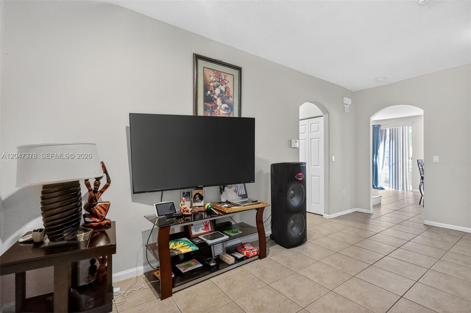 A living room features a wall-mounted television, a glass media console, and tile flooring — 2671 SW 85th Ter # 103, Miramar FL 33025, MIRAMAR, FL