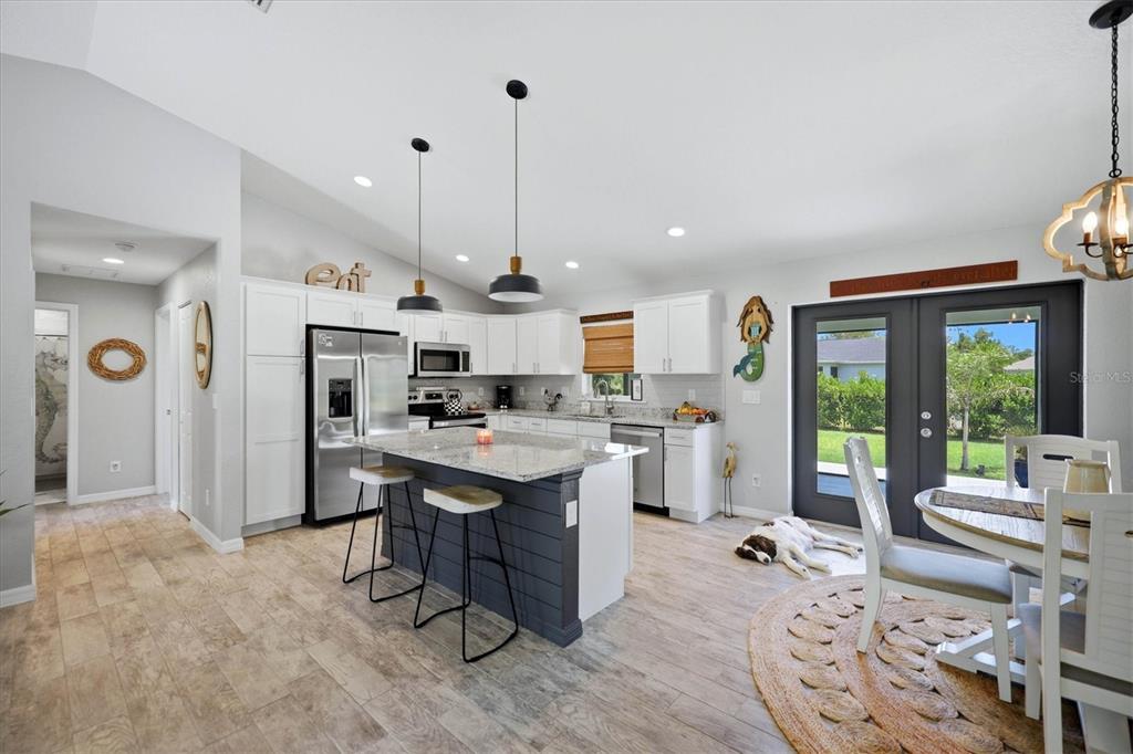 A kitchen features white cabinets, a dark gray island, stainless steel appliances, and tile flooring — 14175 STACKS AVENUE, PORT CHARLOTTE, FL