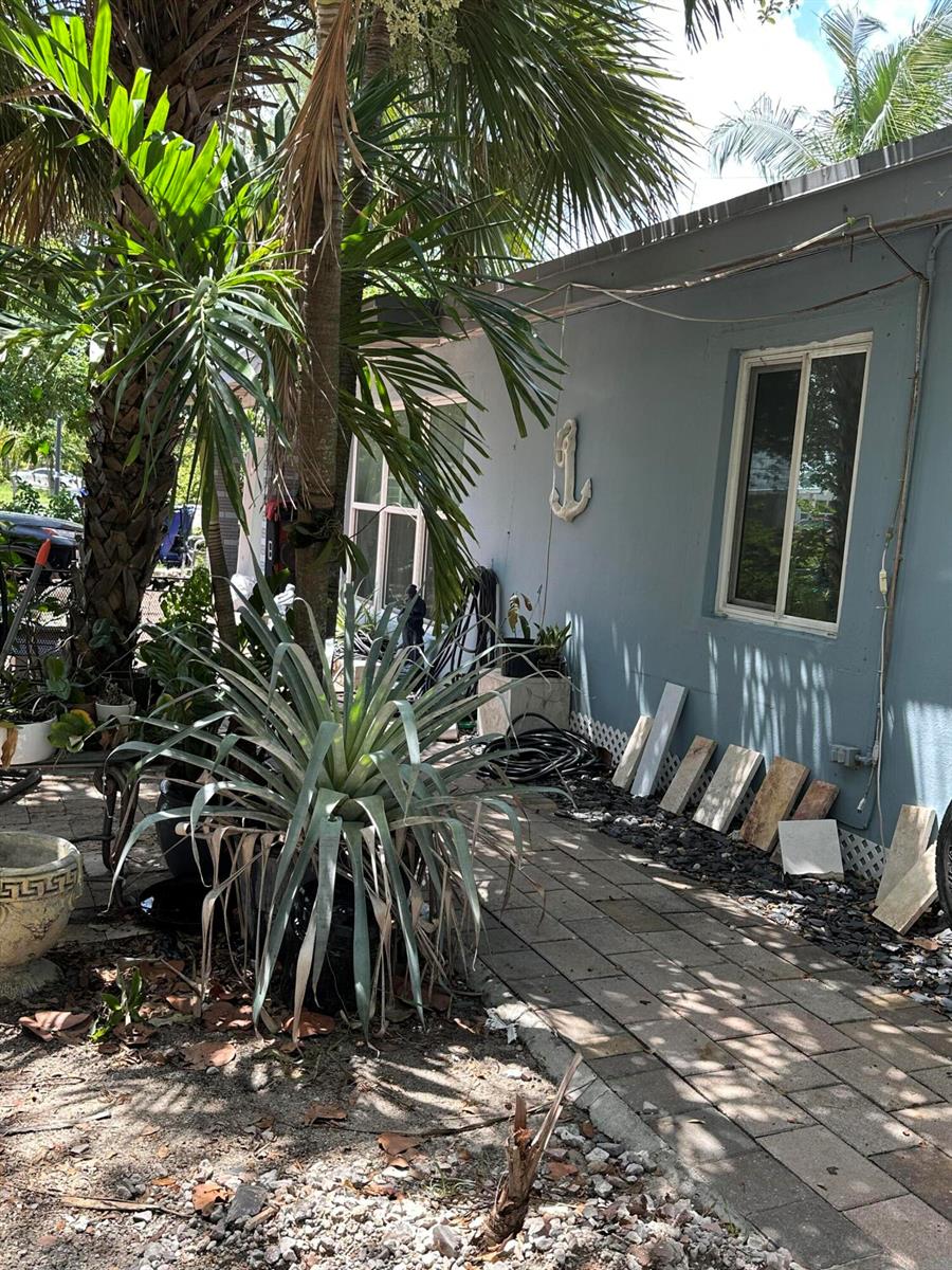 A blue exterior wall features a decorative anchor, a window, and a walkway with pavers — 1571 NE 43rd Street, Pompano Beach FL 33064, POMPANO BEACH, FL