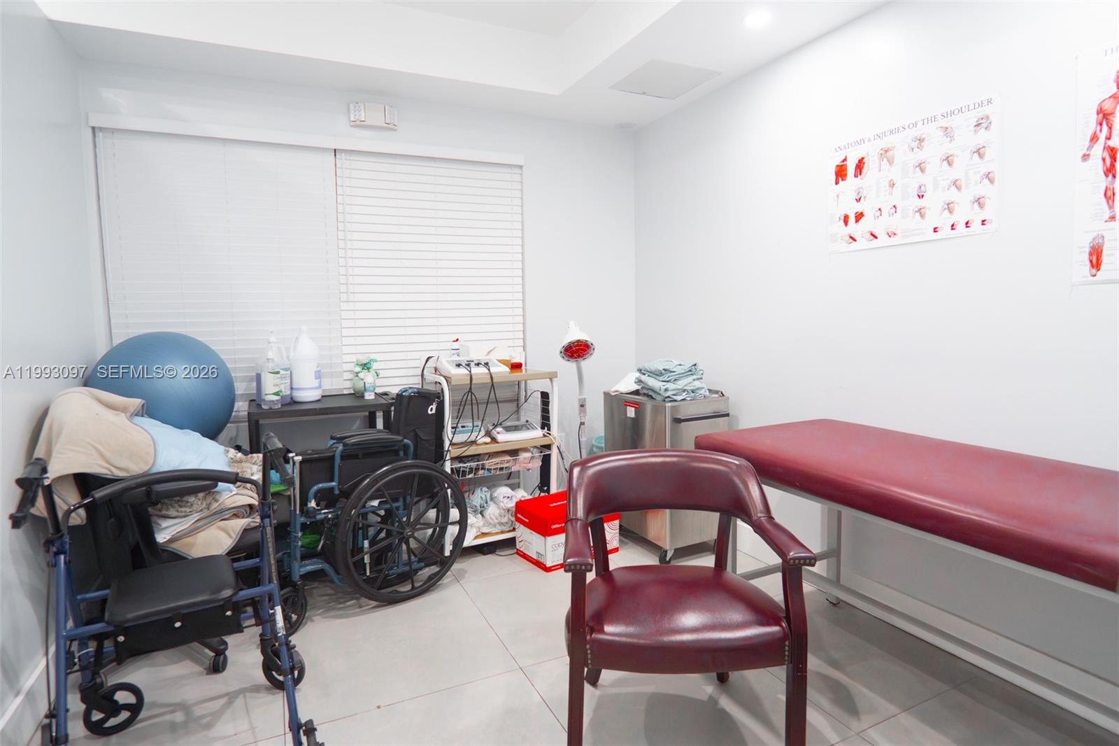 A medical examination room features a treatment table, a wheelchair, a walker, and anatomical charts — 2268 SW 8th St, Miami FL 33135, MIAMI, FL